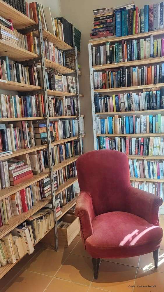 Rayonnages de livres et fauteuil de lecture à la bibliothèque de Saint-Hilaire d’Ozilhan